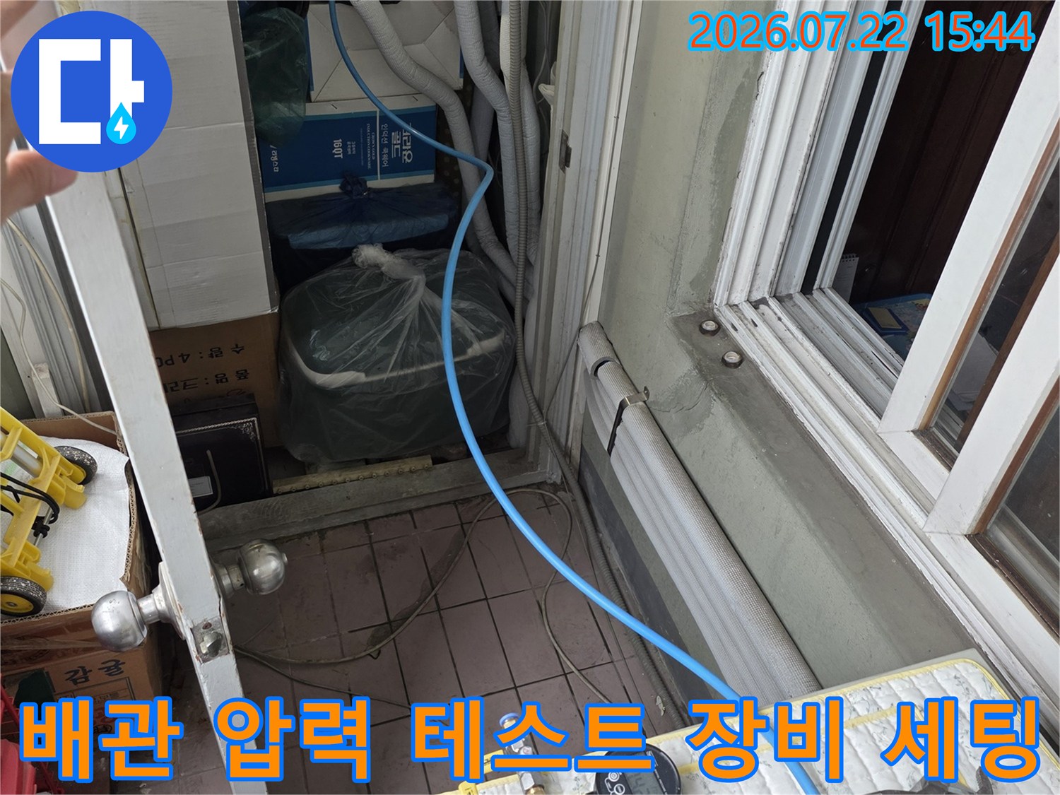 디지털 압력계와 아날로그 게이지가 연결된 누수 탐지 장비 - 파란색 호스가 배관에 연결된 모습