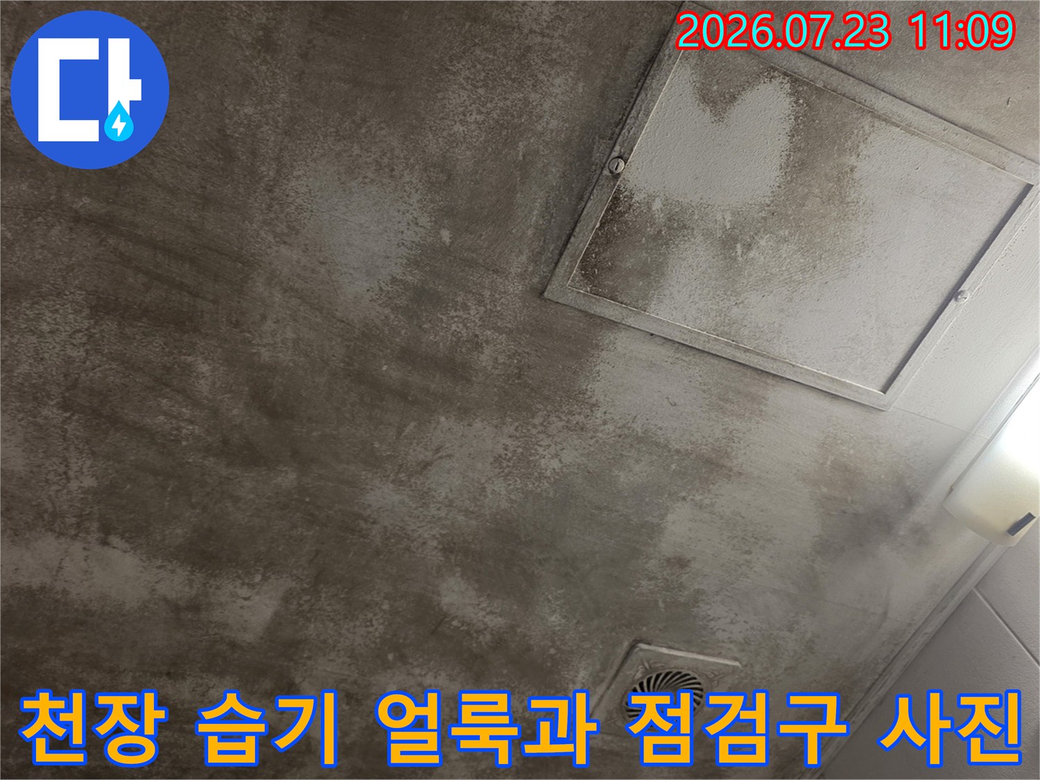 전체적으로 눅눅하게 젖어 있는 천장 모습과 내부 확인용 사각 점검구가 보이는 각도