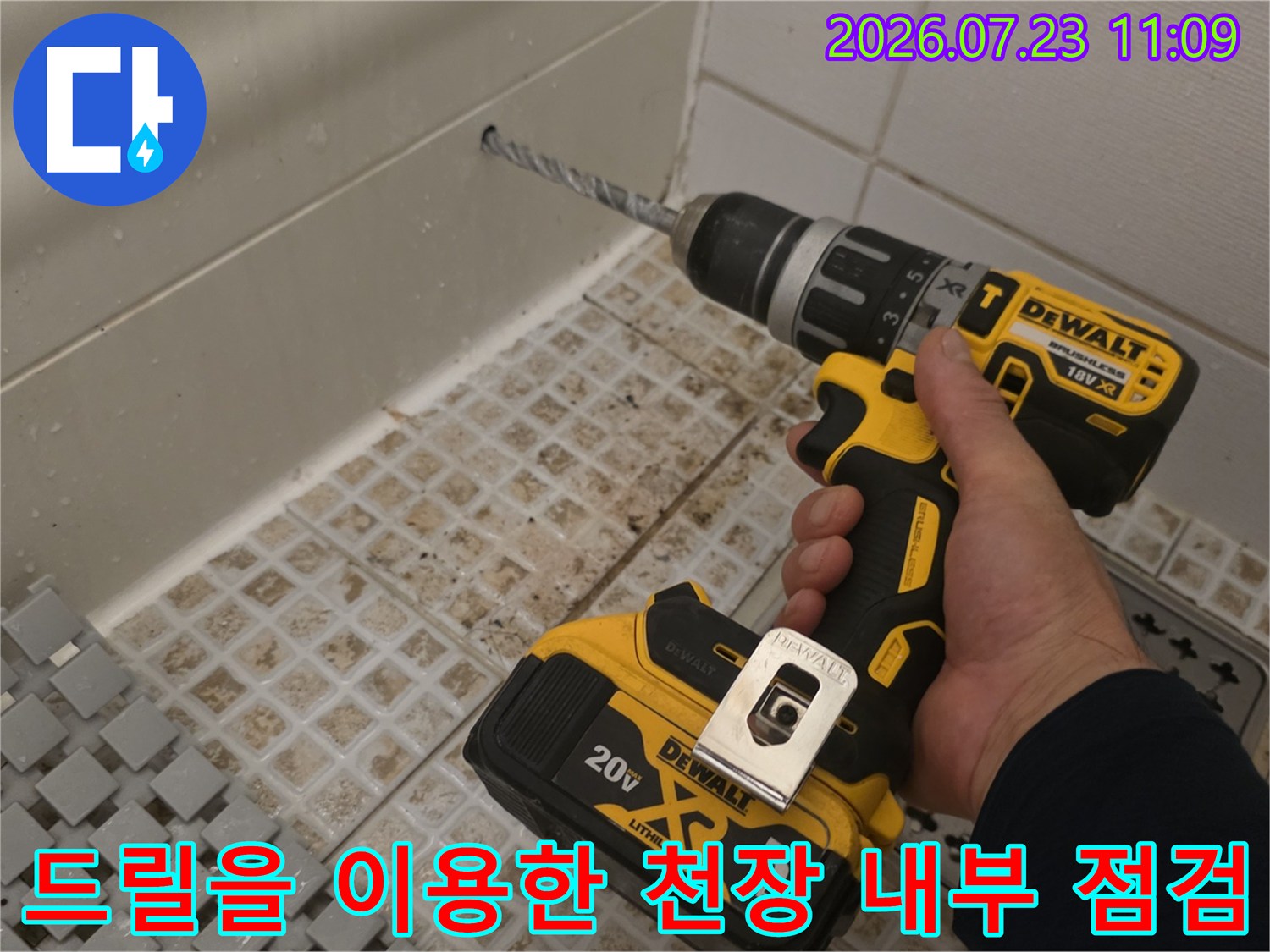 흰색 타일이 시공된 공간에서 전동 드릴로 천장을 뚫고 있는 작업 장면