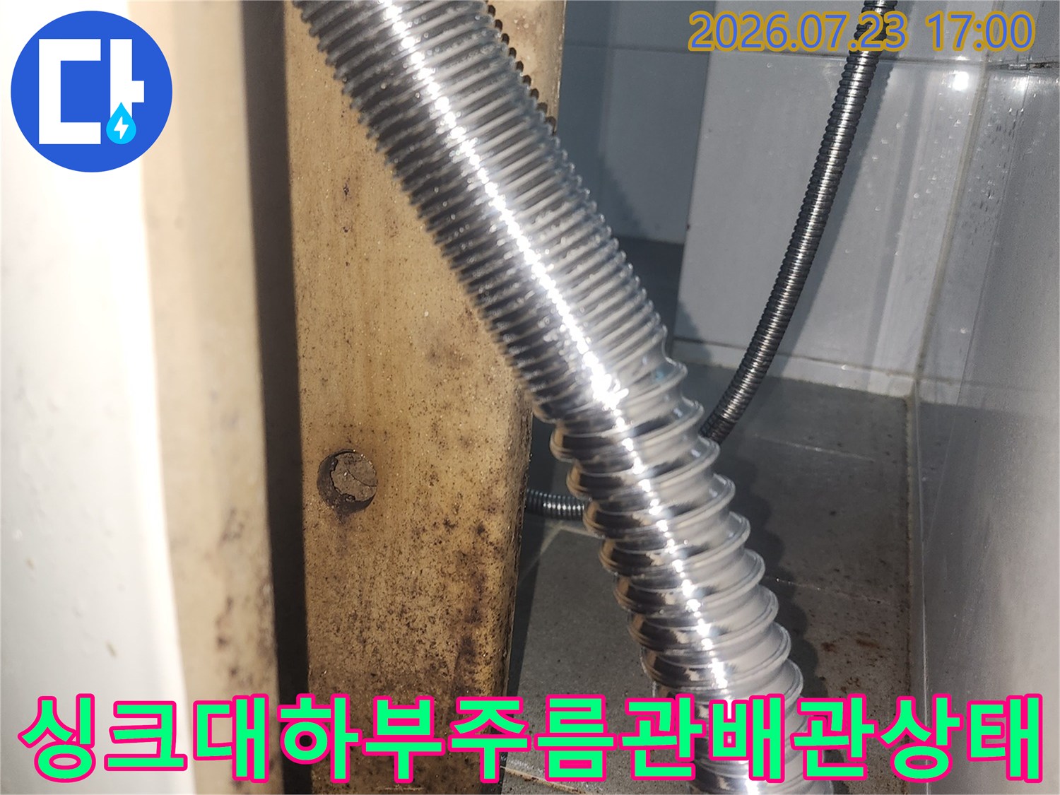 싱크대 하단에 설치된 은색 주름관 배관과 연결 부위-누수 점검 모습