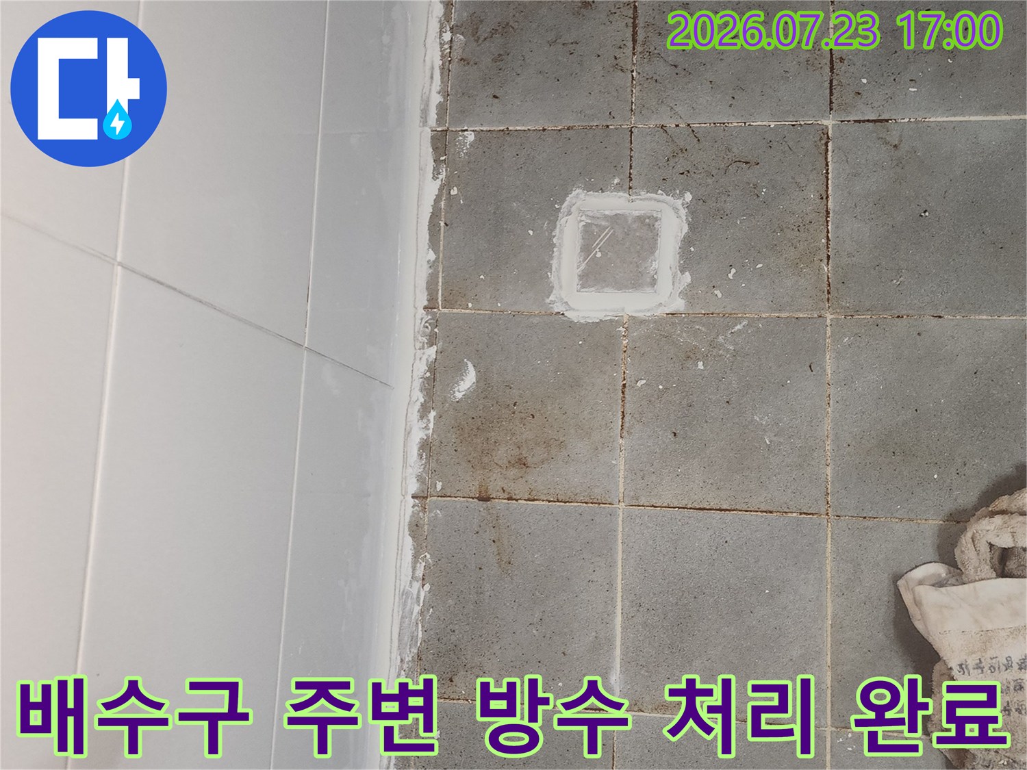 회색 타일 바닥의 유가 부위에 하얀색 보수재가 칠해진 모습-화장실 누수 공사
