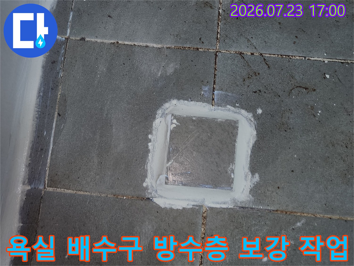 회색빛 타일 사이의 사각형 배수구 주변에 하얀색 방수재가 발라진 사진
