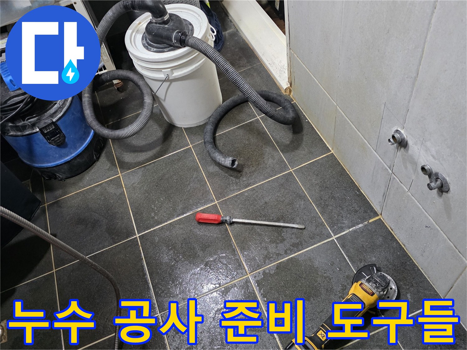 공사 중인 세탁실 바닥의 타일 제거 부위와 작업 장비