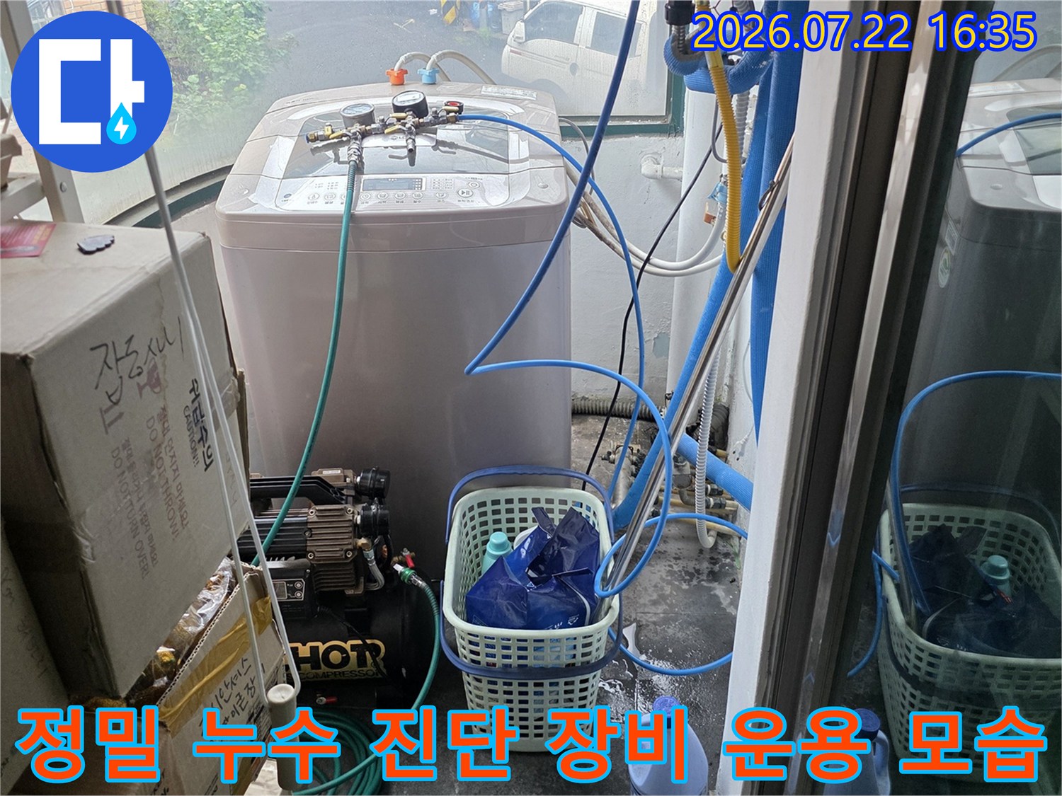 세탁실 바닥에 놓인 누수 탐지 장비와 배관으로 이어지는 파란색 호스들