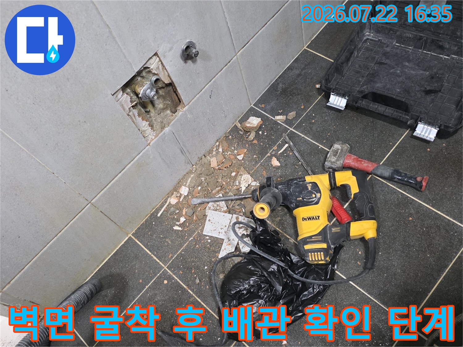 타일 벽면을 일부 파내어 내부의 누수 배관 연결 부위를 확인하고 있는 작업 장면
