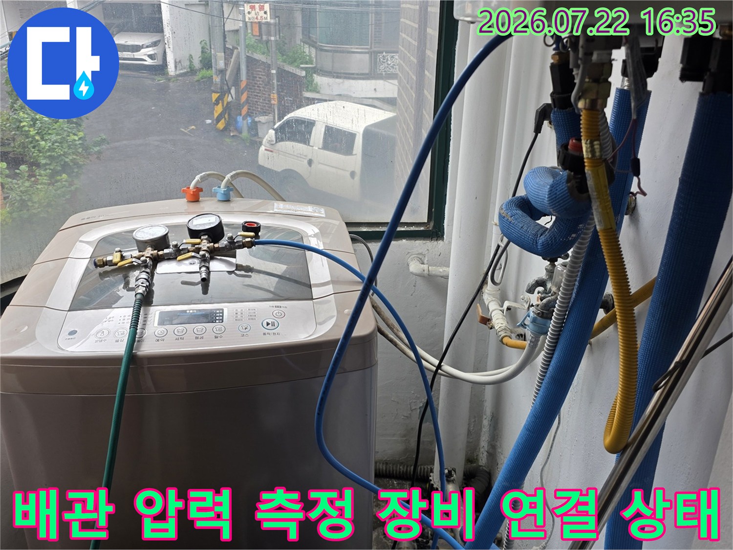 파란색 호스와 압력 게이지가 연결된 누수 탐지 장비가 세탁실에 배치된 사진