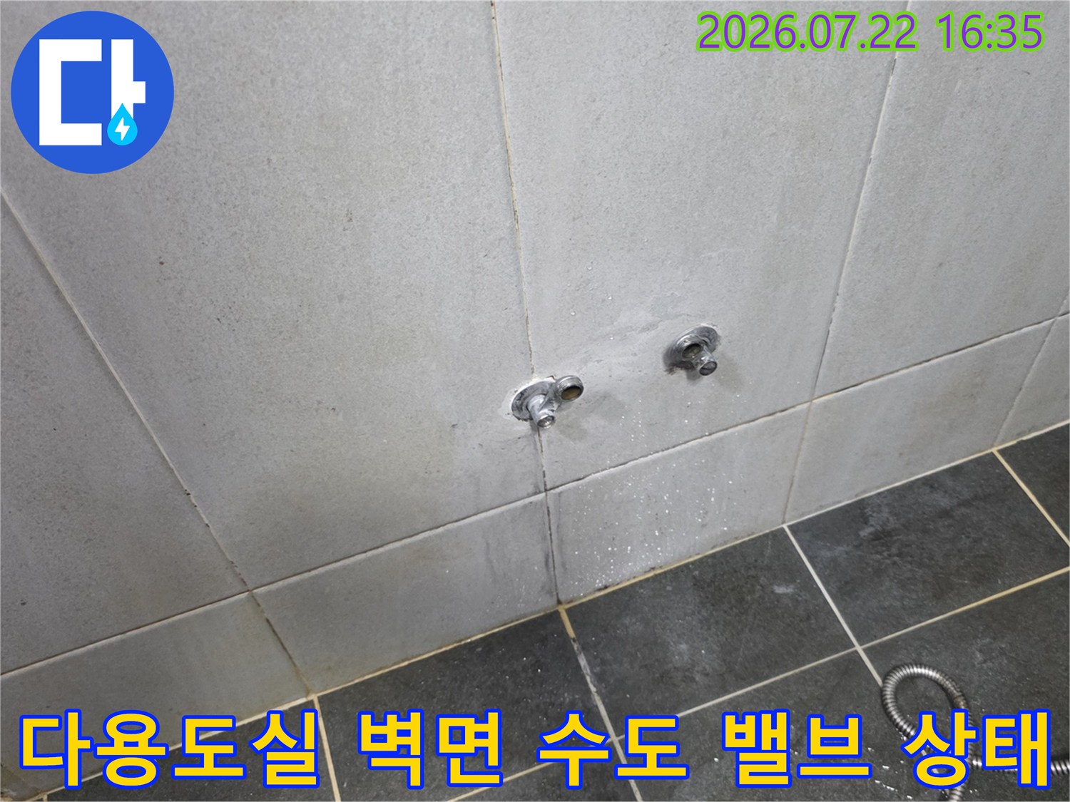 회색빛 타일 벽에 설치된 두 개의 수도꼭지와 바닥의 연결 호스-현장 진단 사진