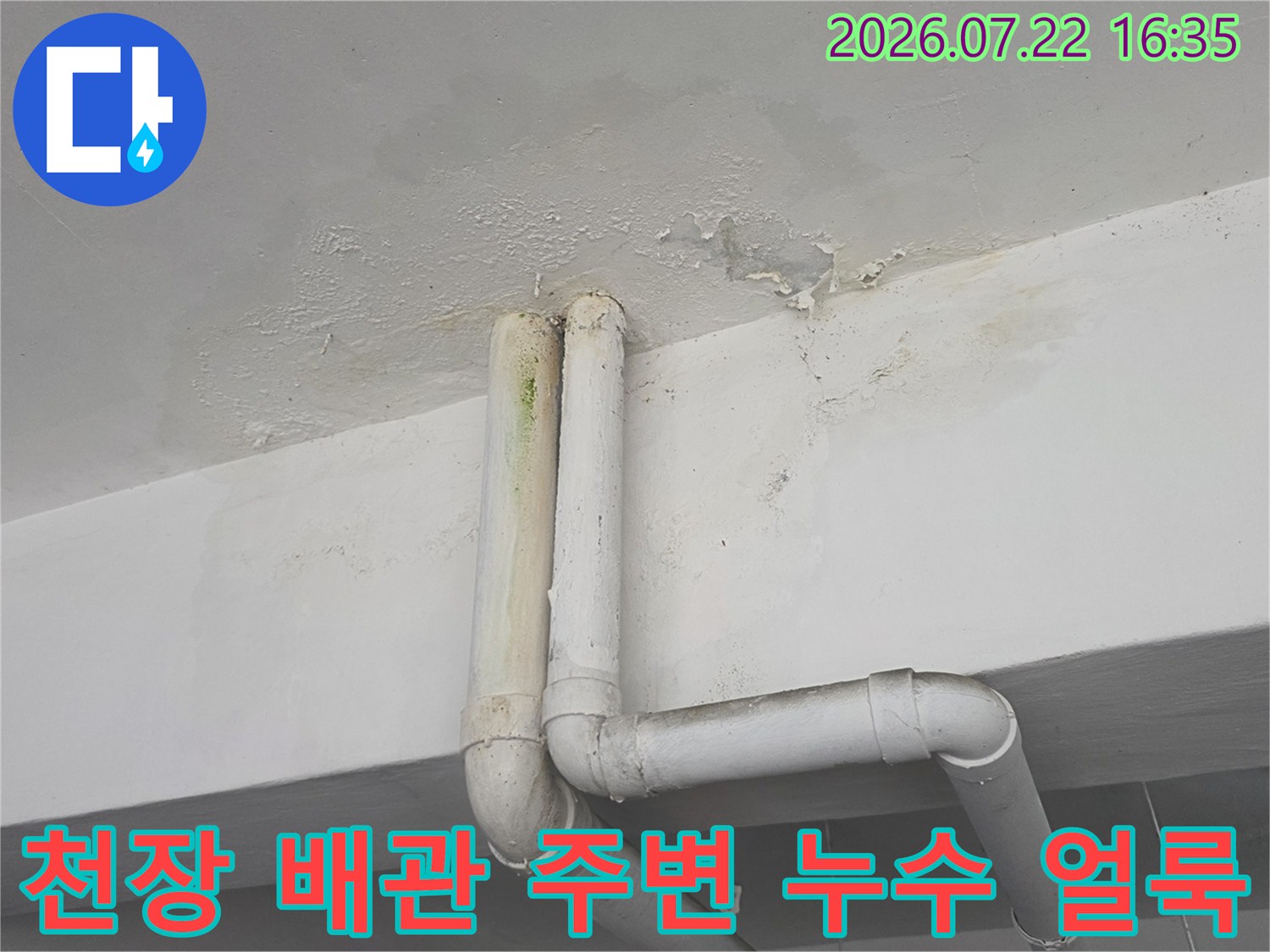 흰색 천장 배관 연결 부위 주변으로 물이 스며들어 발생한 갈색 얼룩과 페인트 들뜸 현상