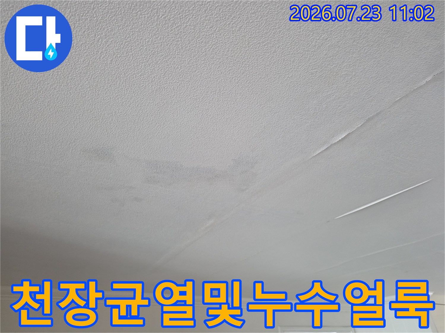 흰색 거실 천장에 발생한 회색빛 누수 얼룩-그리고 갈라진 틈새 모습