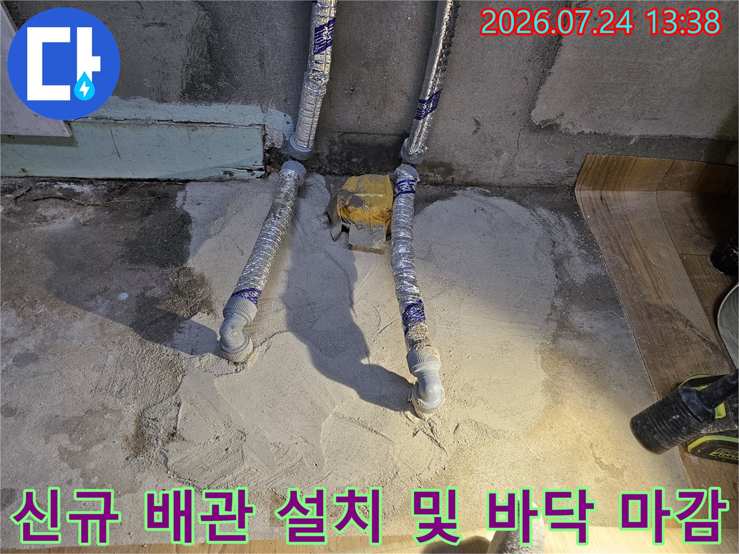 새로 교체된 흰색 배관이 바닥에 매립되기 전 미장 작업으로 덮여 있는 현장 사진