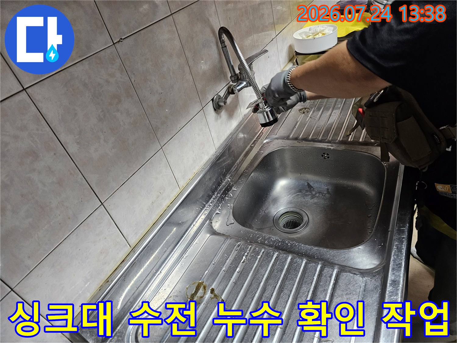 주방 싱크대 수전 부위에서 누수 여부를 꼼꼼하게 점검하고 있는 엔지니어의 손 모습