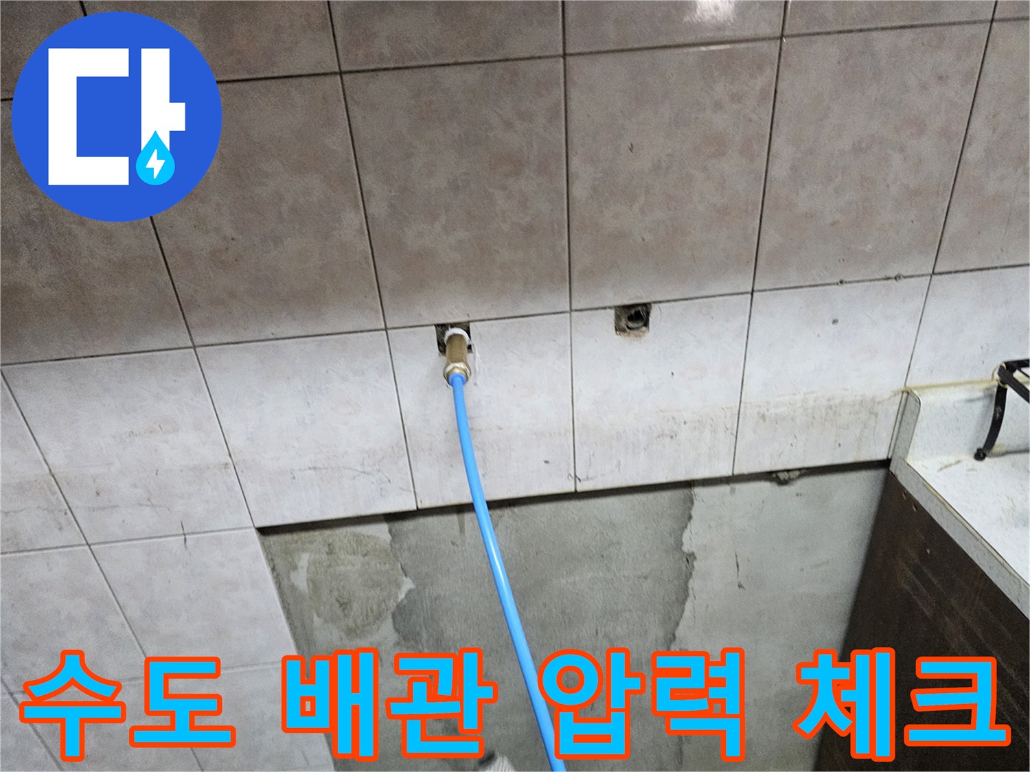 타일 벽면 배관 입구에 연결된 파란색 공압 테스트 호스