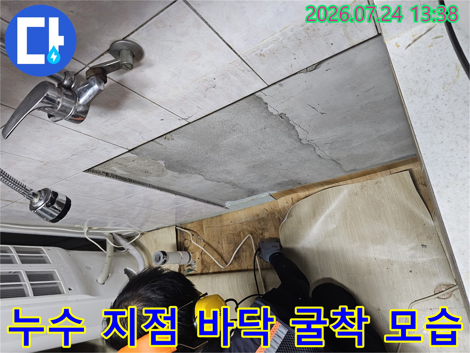 화장실 수도꼭지 아래쪽 바닥 타일을 제거하고 내부 시멘트 층을 드러낸 누수 탐지 현장 사진
