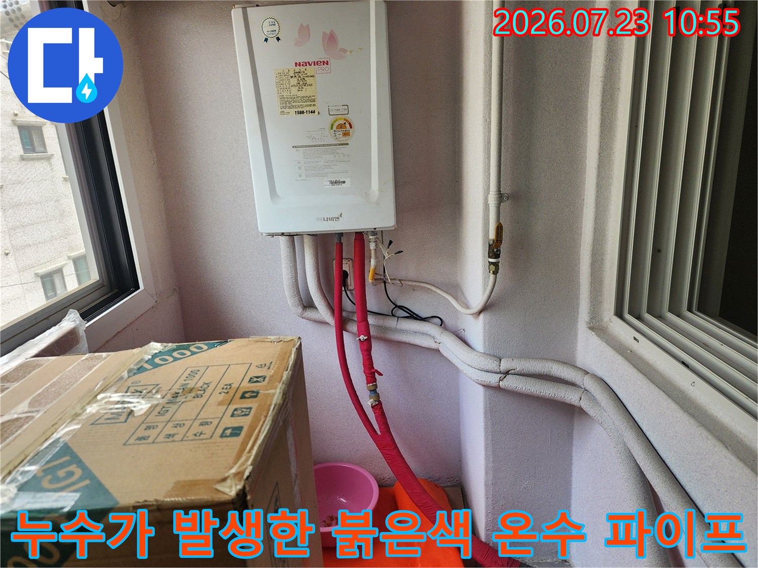 흰색 벽지를 배경으로 설치된 가스 보일러와 그 하단에 연결된 빨간색 배관 사진