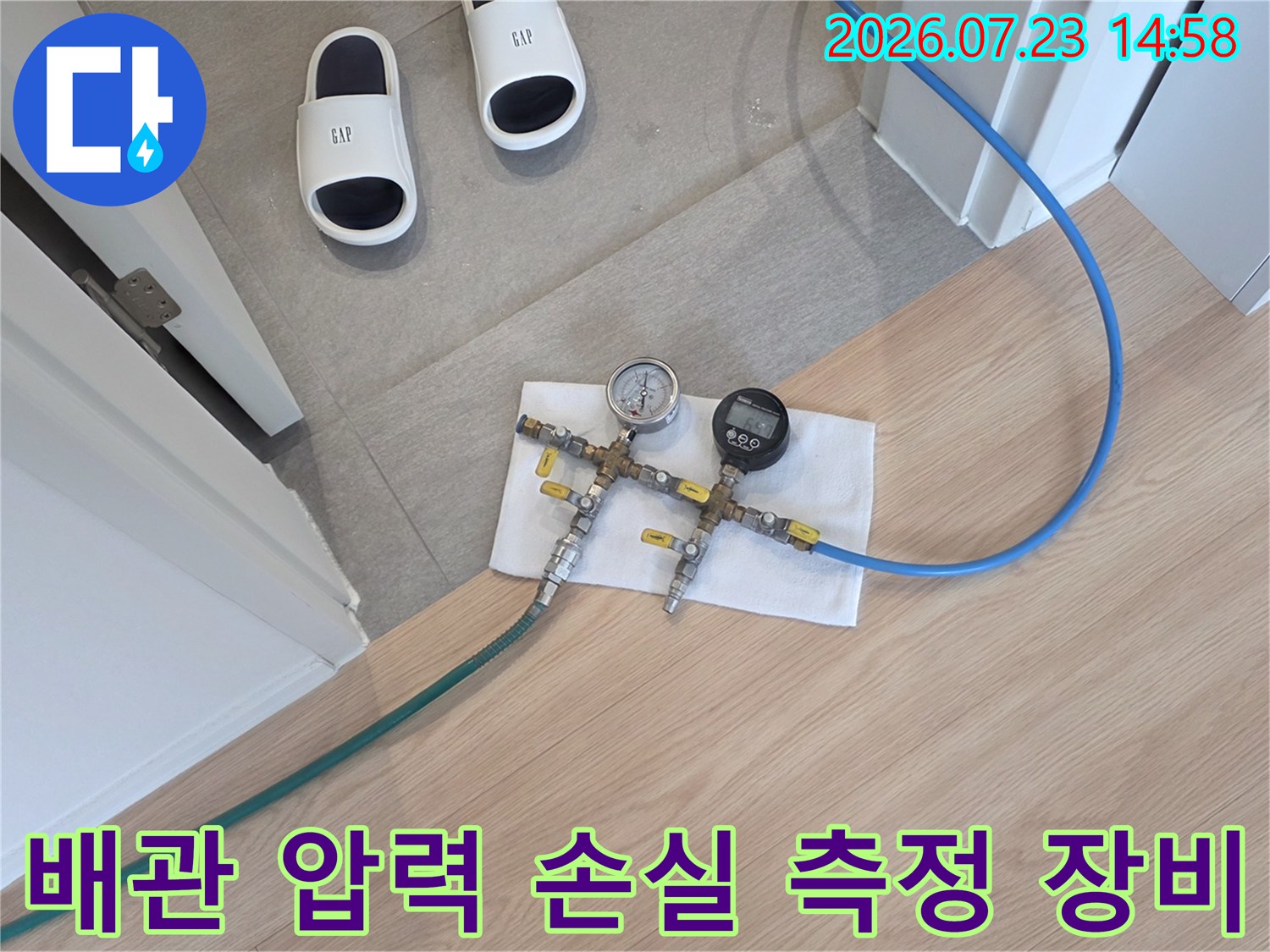 금속 밸브와 두 개의 압력계가 연결된 장비가 바닥 수건 위에 놓여 있는 사진