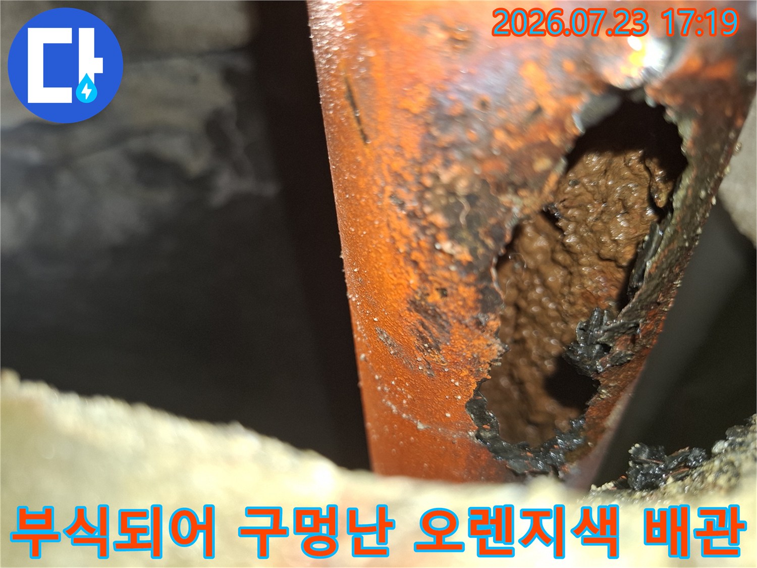 오렌지색 배관 외벽이 심하게 부식되어 커다란 구멍이 뚫린 모습-누수 지점 확인