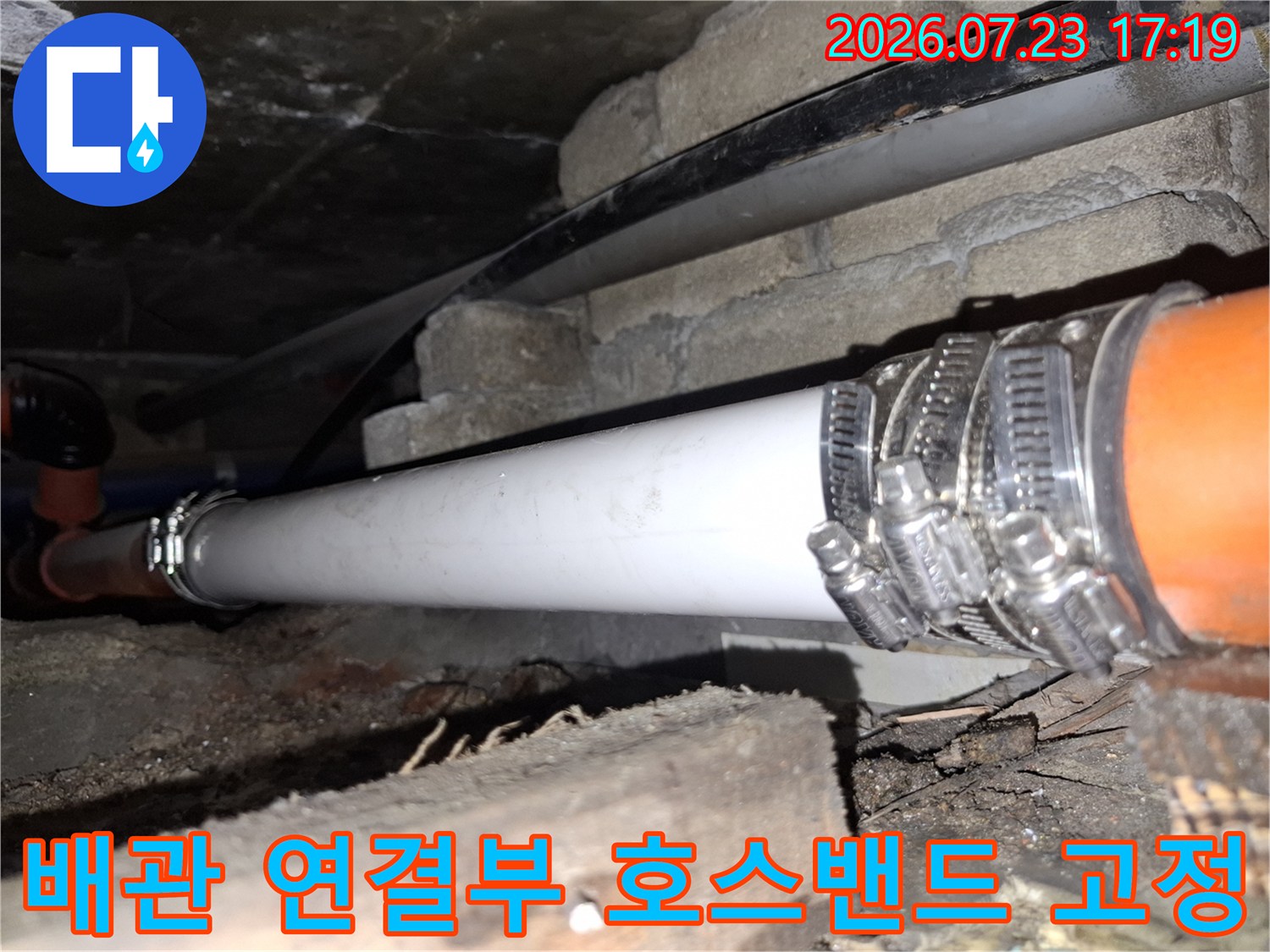 오렌지색 배관과 흰색 배관을 연결하고 금속제 호스 밴드로 단단히 조인 모습