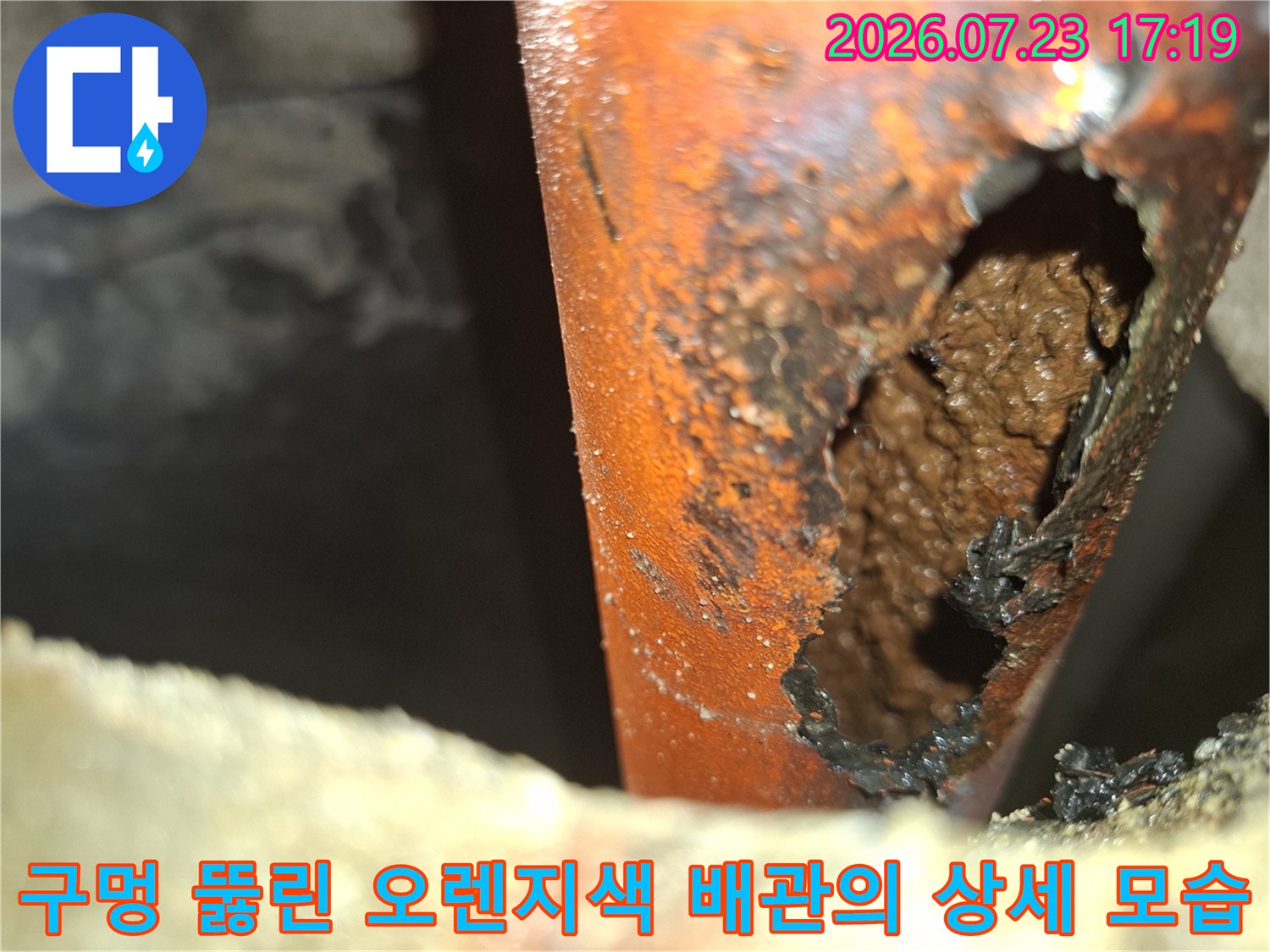 오렌지색 플라스틱 계열 배관에 부식으로 인한 커다란 구멍이 생긴 모습