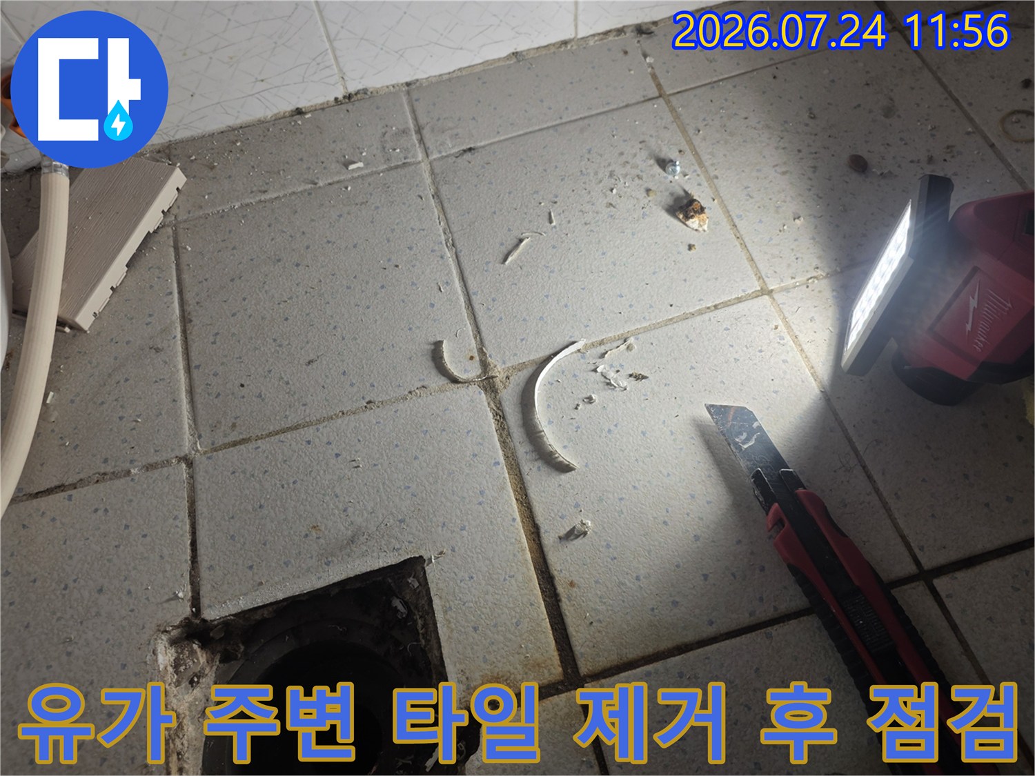 부서진 타일 조각과 노출된 배수구 근처를 진단하는 모습