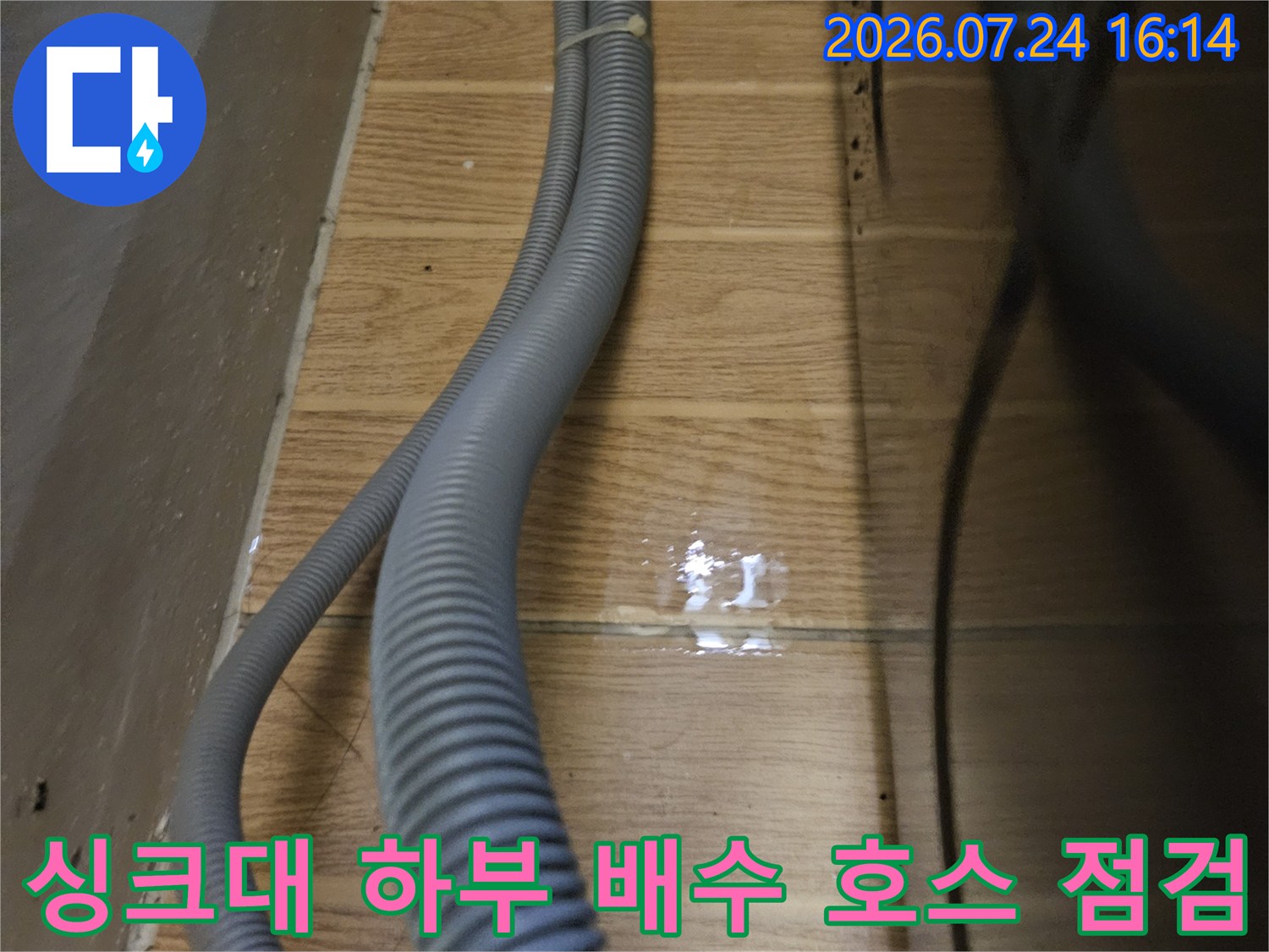 싱크대 아래 위치한 회색 배수 호스와 벽면 연결 부위의 정밀 점검 모습