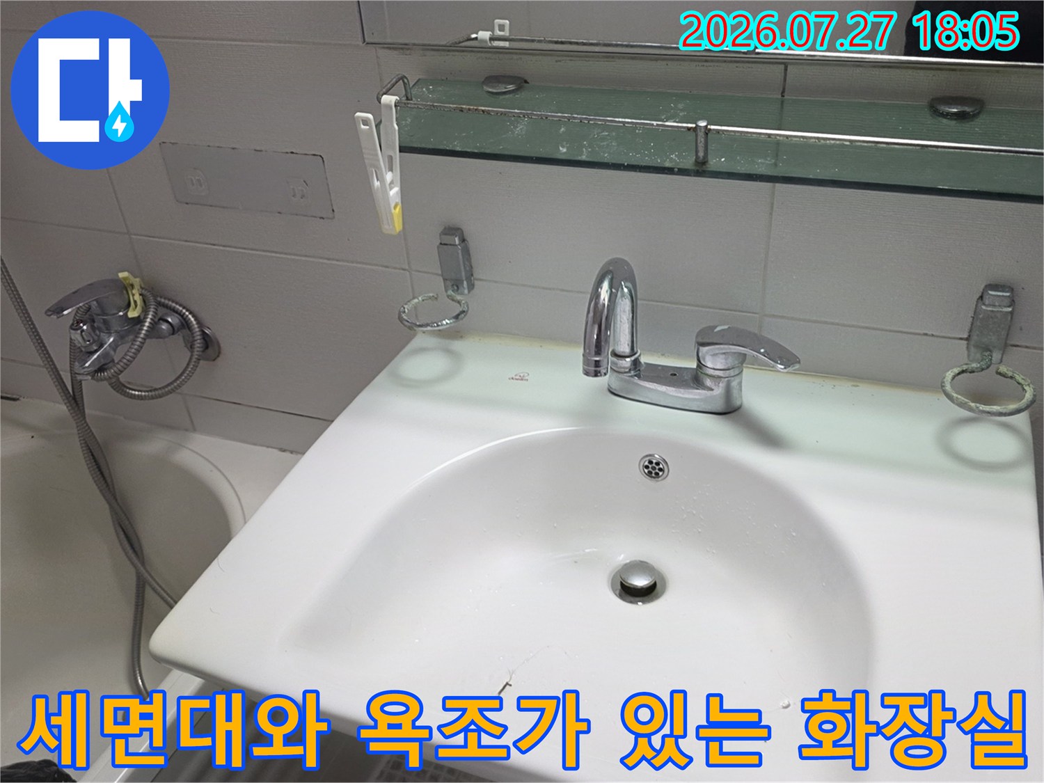 흰색 도기 세면대와 금속 수전 그리고 왼쪽에 위치한 욕조-욕실 내부 모습