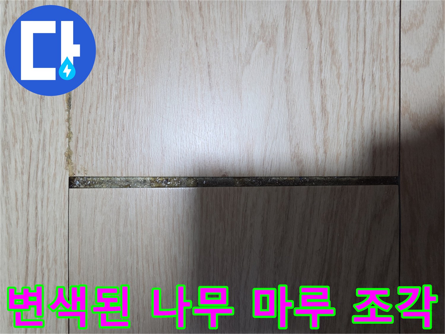 수분 침투로 인해 어두운 얼룩이 생긴 마루 자재 사진입니다.