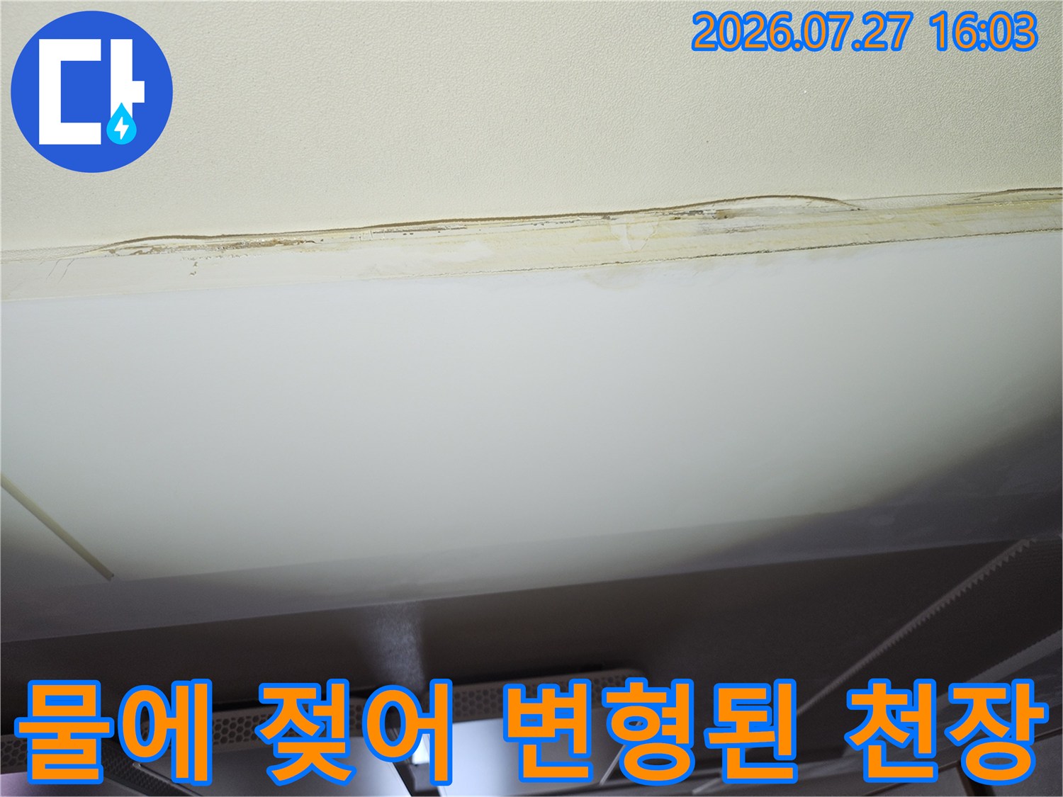 거실 천장의 흰색 마감재가 누수로 인해 노란 얼룩이 생기고 들뜬 모습