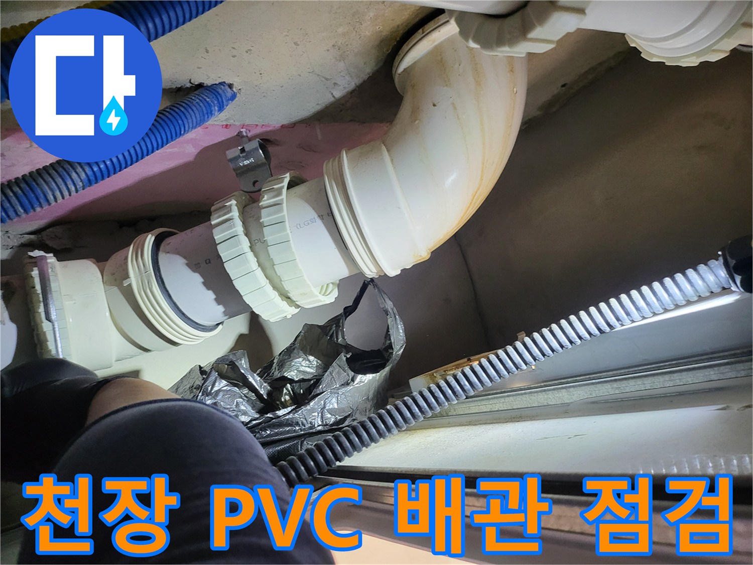 화장엘 천장 내부의 흰색 오수 배관과 파란색 주름관 연결 부위