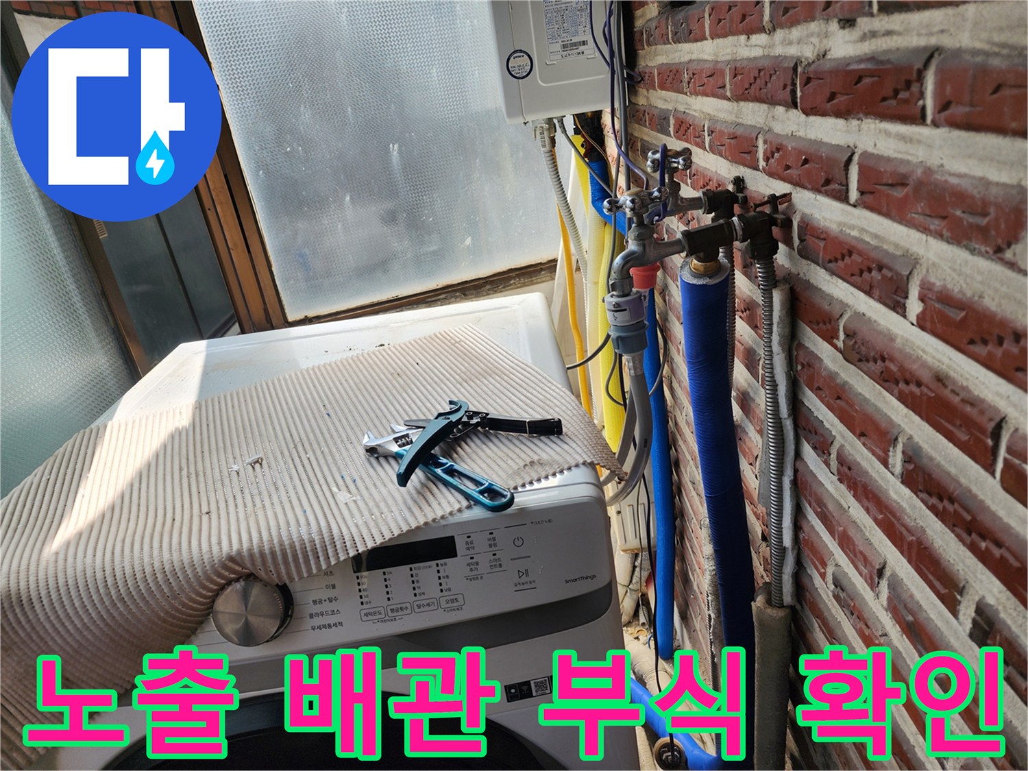 벽돌 외벽에 연결된 파란색 보온재 배관과 밸브 장비