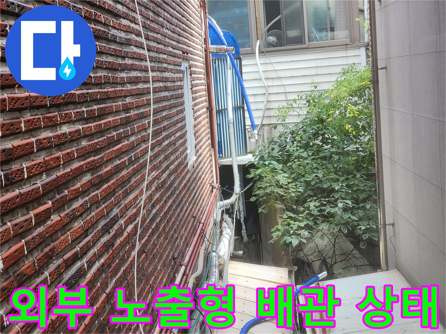 붉은 벽돌 외벽의 배관과 훼손된 보온재 상세 사진