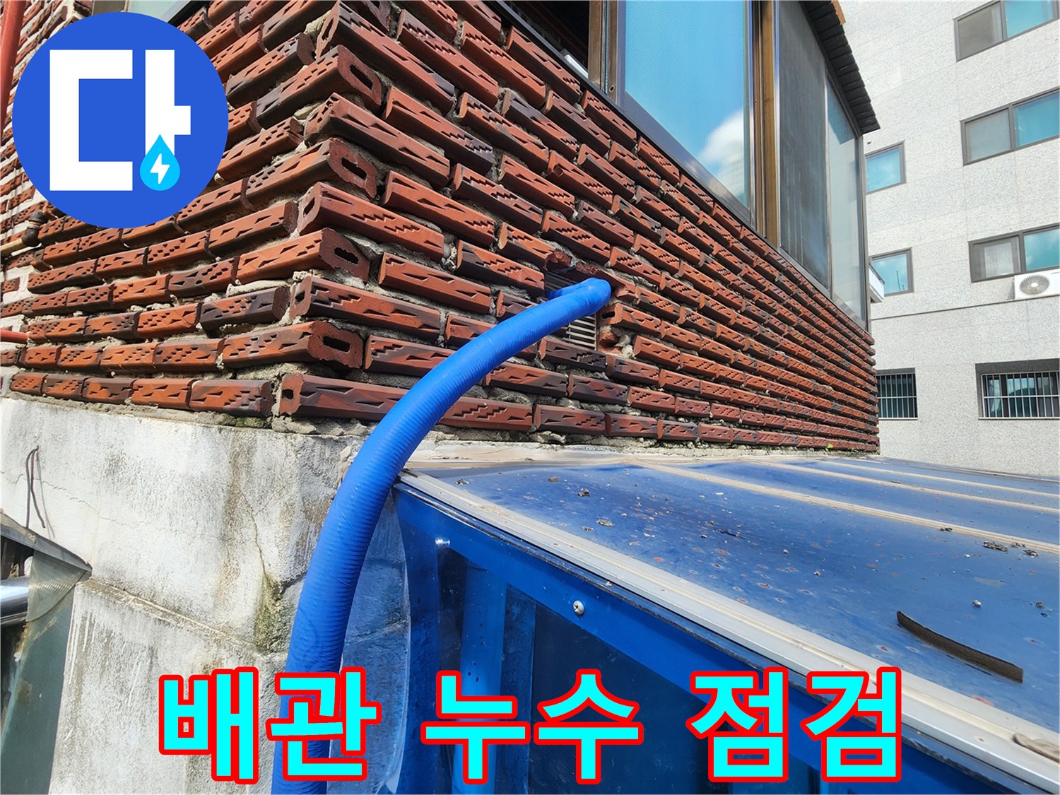 파란색 보온재로 감싸진 배관이 외벽 틈새에 위치한 모습