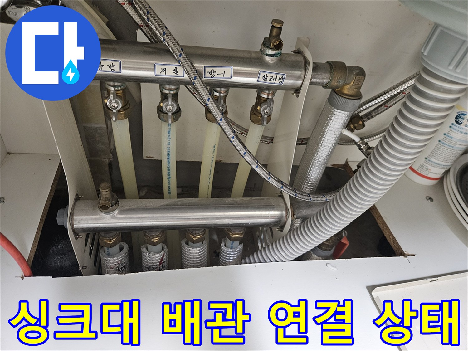 싱크대 하부의 금속 지지대와 연결된 각종 배관 및 호스들