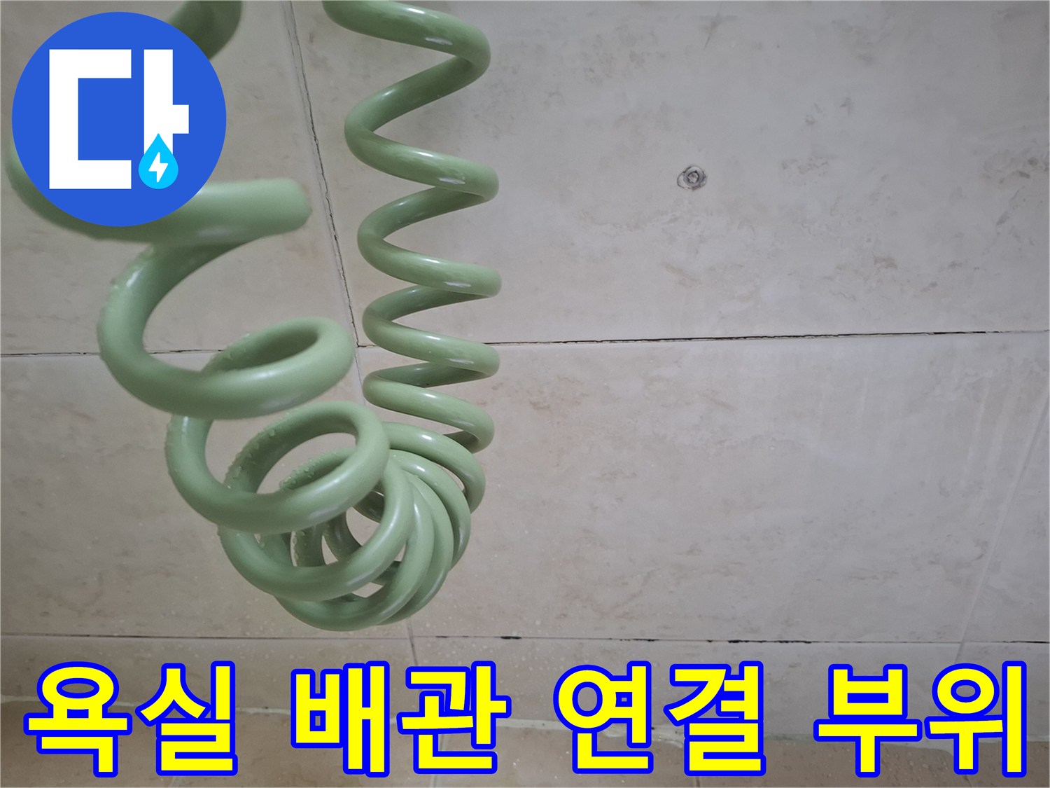 욕실 세면대 하부의 초록색 배관과 타일 벽면 모습입니다.