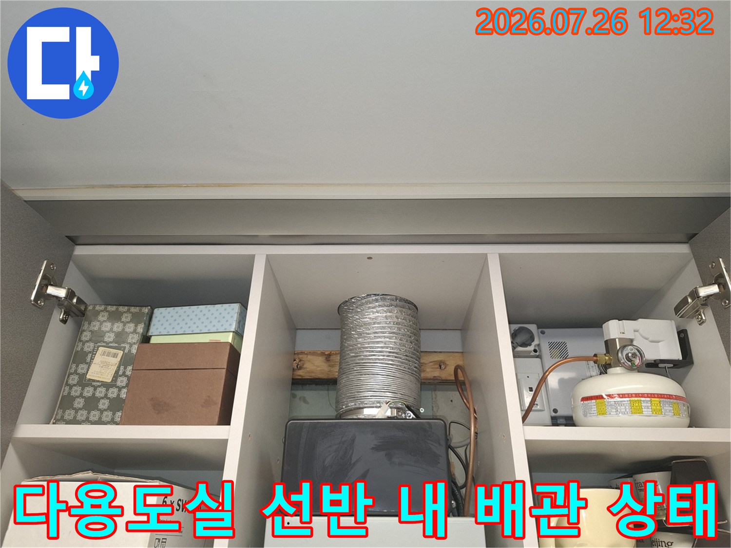 다용도실 수납장 내부의 은색 자바라 배관-가스보일러와 가스통이 배치된 모습