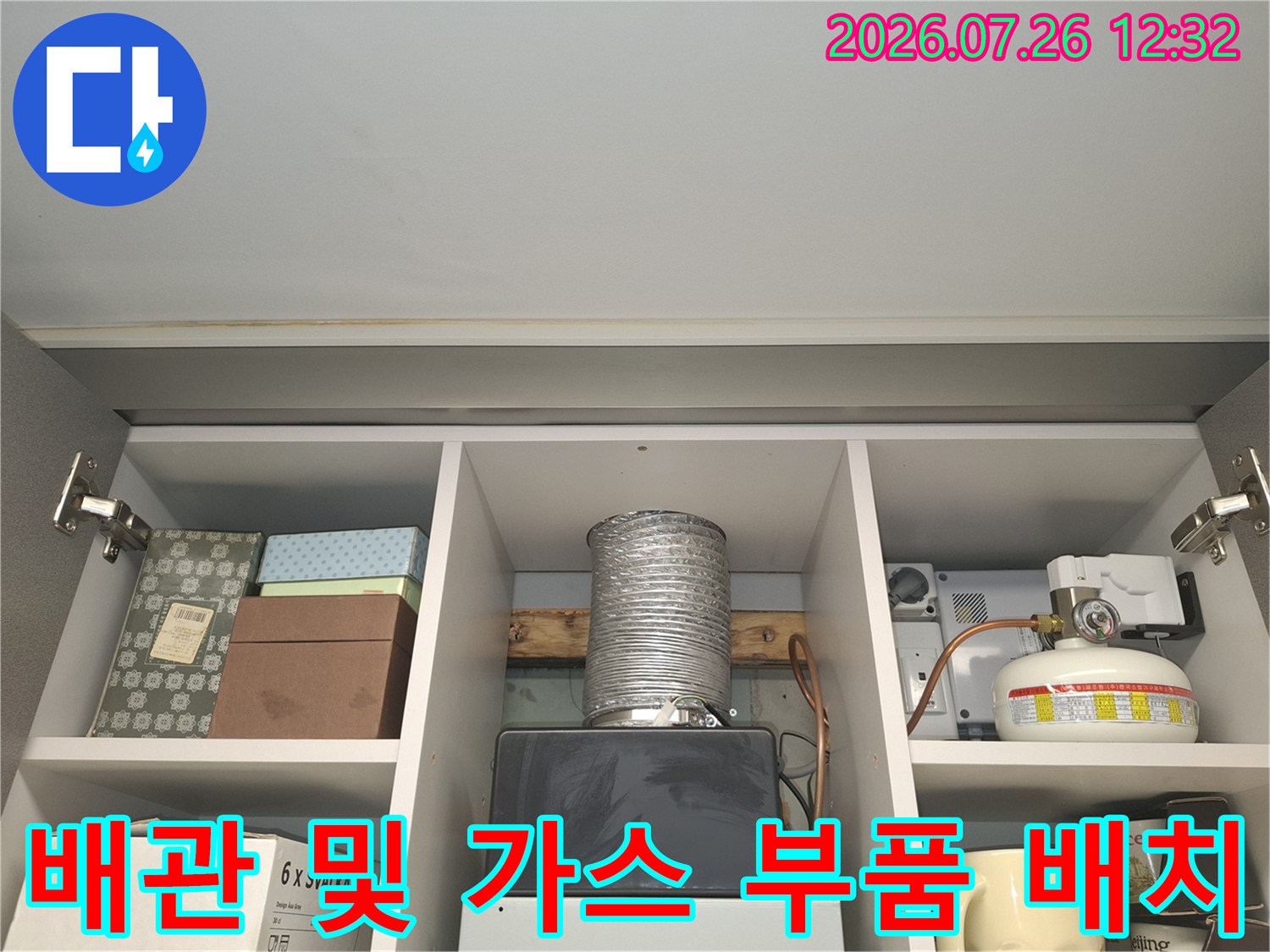 수납장 칸 내부에 설치된 은색 주름 배관과 흰색 가스 보일러 장치-모습