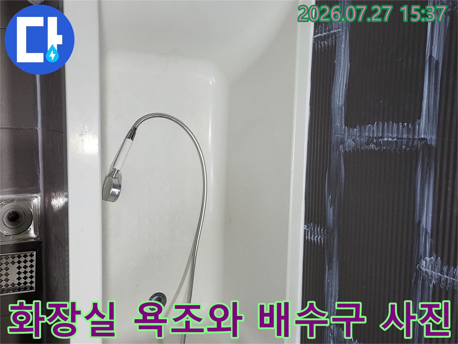 흰색 욕조 속에 샤워기가 있고 바닥에는 유가-배수구가 위치한-전경