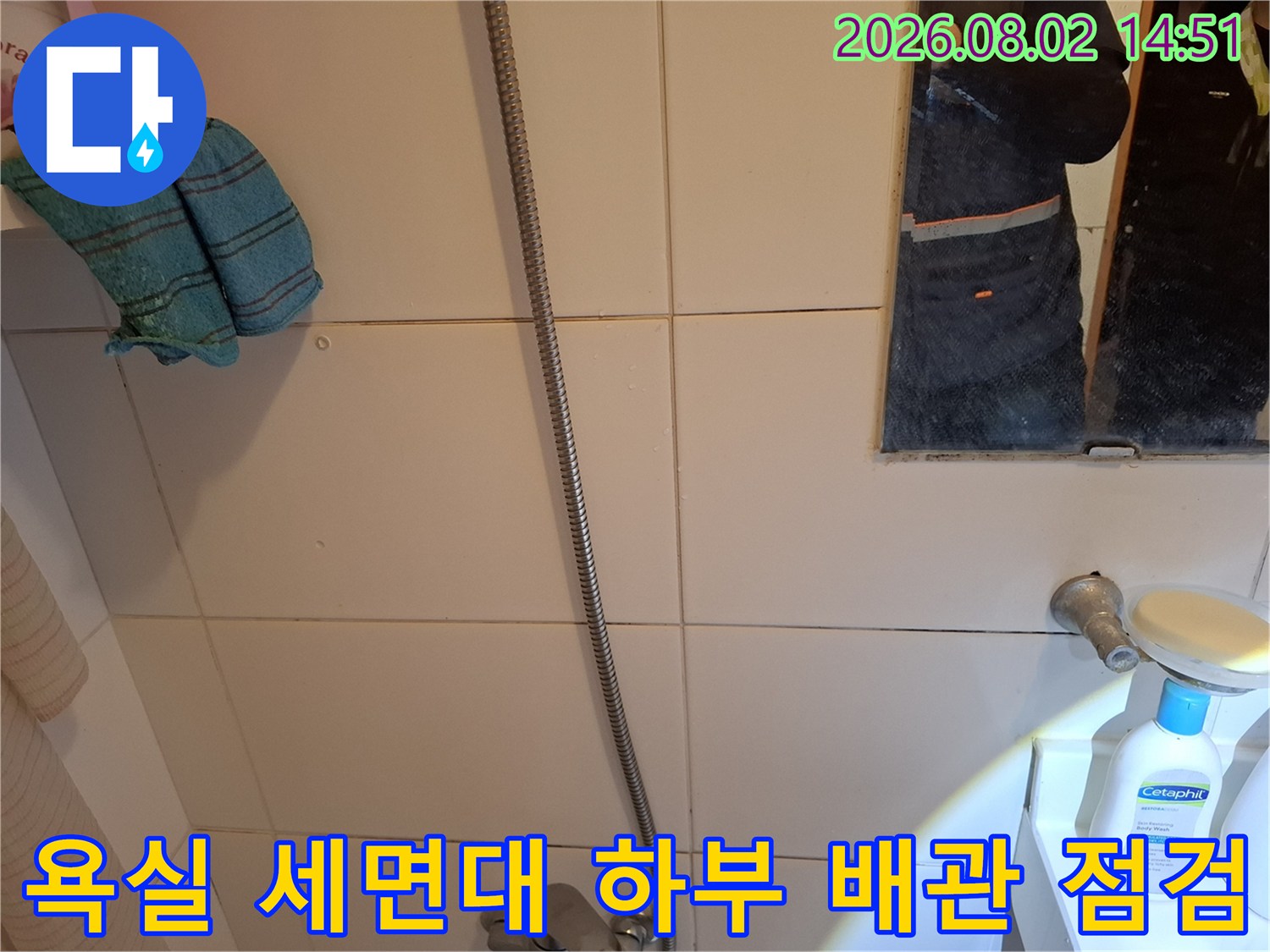 세면대 밑 배관과 벽 타일의 접촉 부위를 정밀하게 조사하는 모습