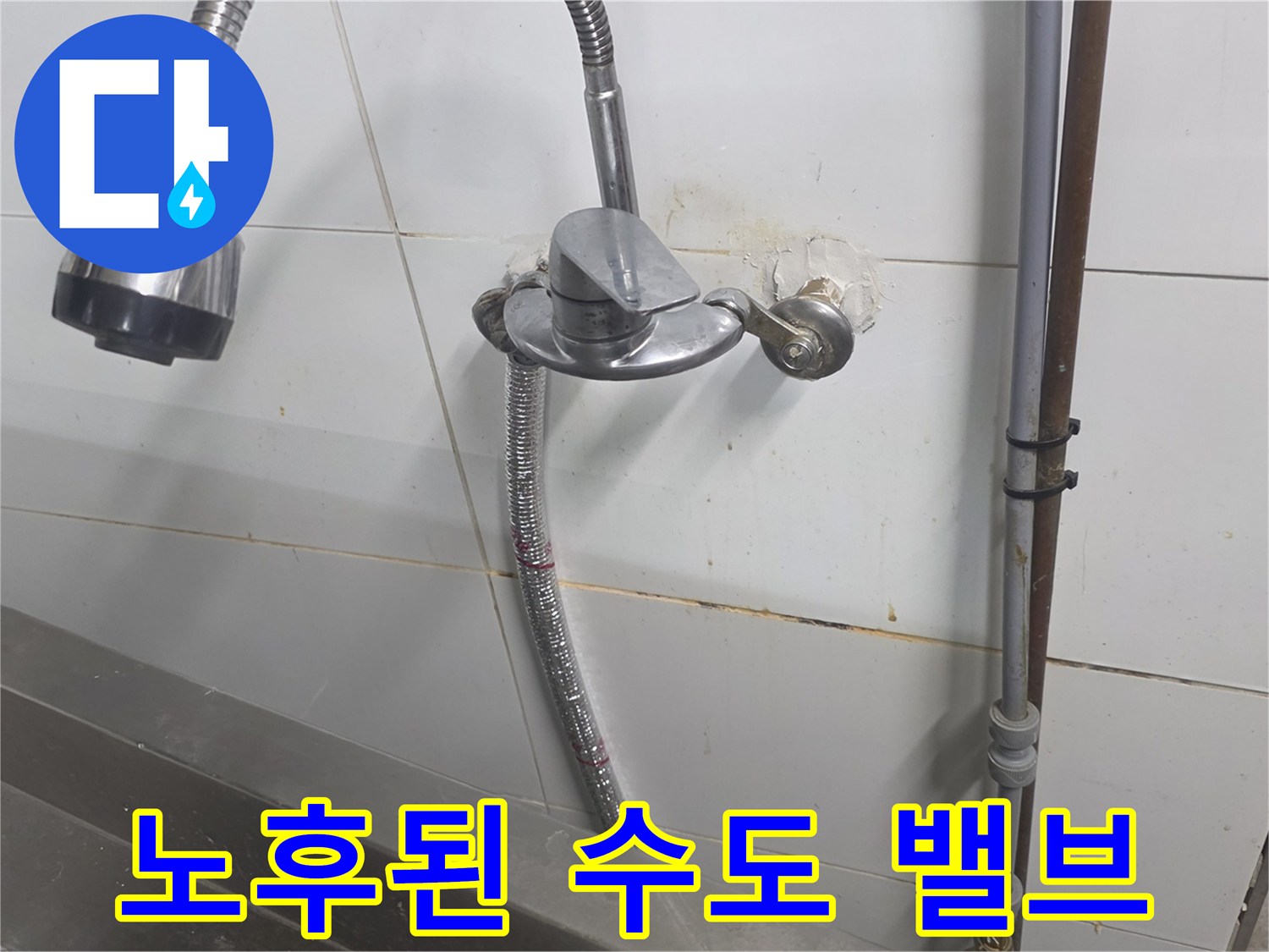 벽면 타일에 설치된 노후된 수도 밸브와 배관 연결부