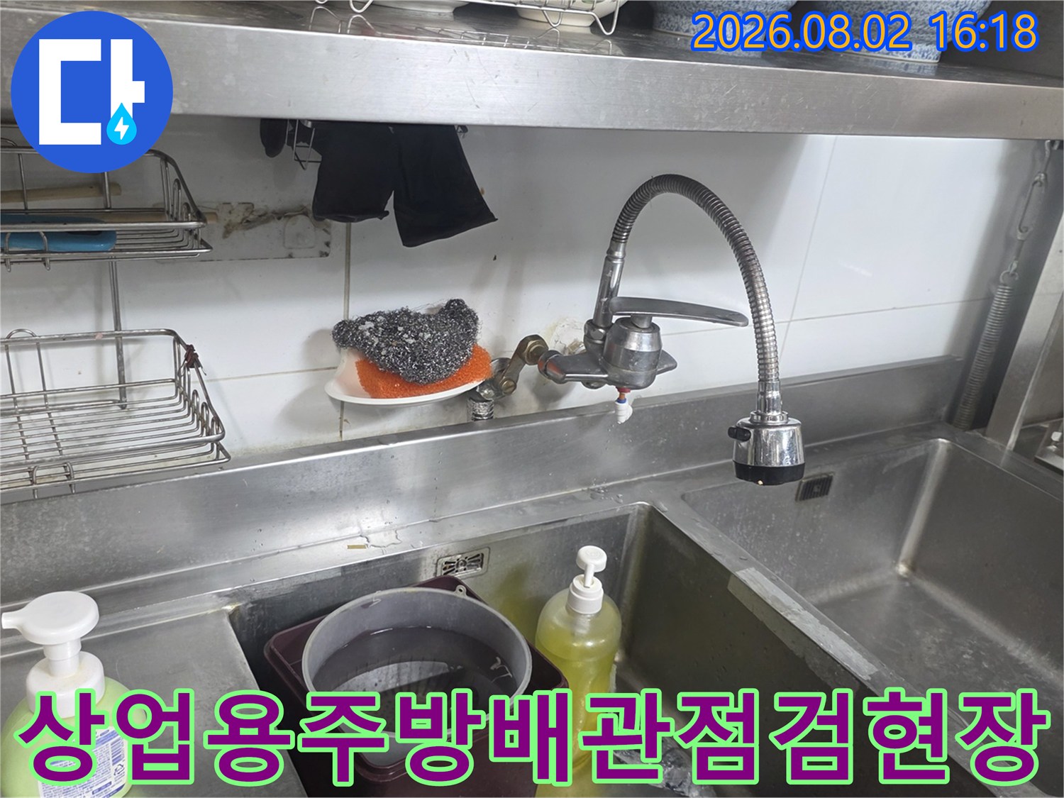 상업용 주방 싱크대 하단부의 노출된 수도 배관과 수전 연결 부위 점검 모습