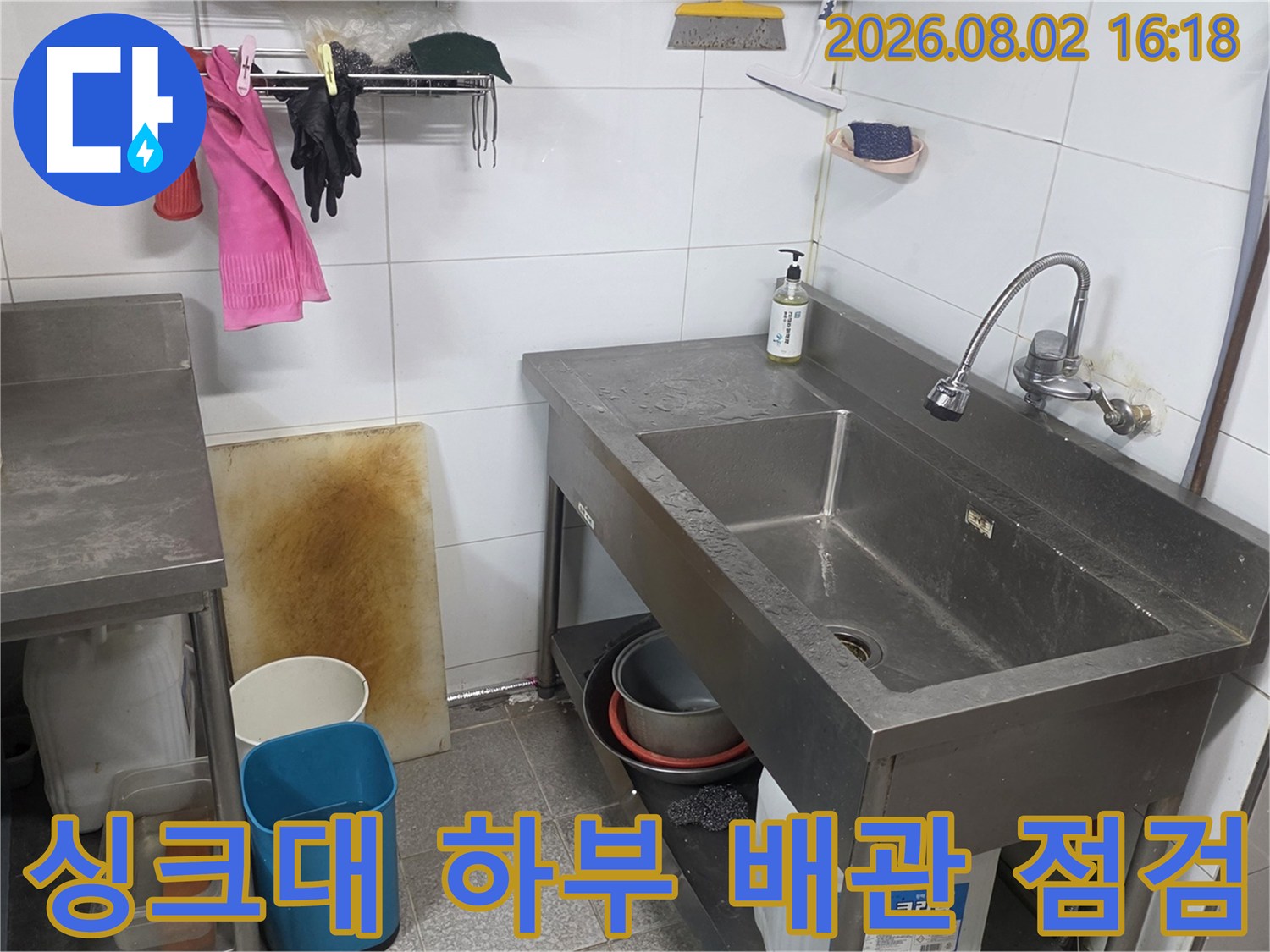 스테인리스 싱크대 아래쪽의 노출된 배관과 주변 환경