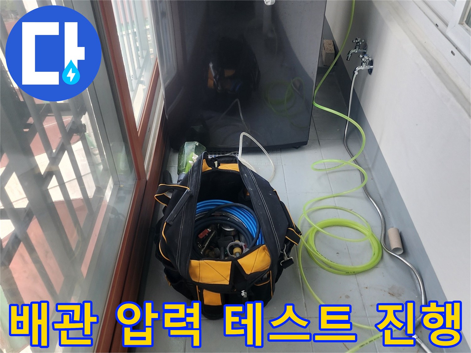 검은색 케이스의 진단 장비와 연결 호스가 세탁실 바닥에 놓여 있습니다.