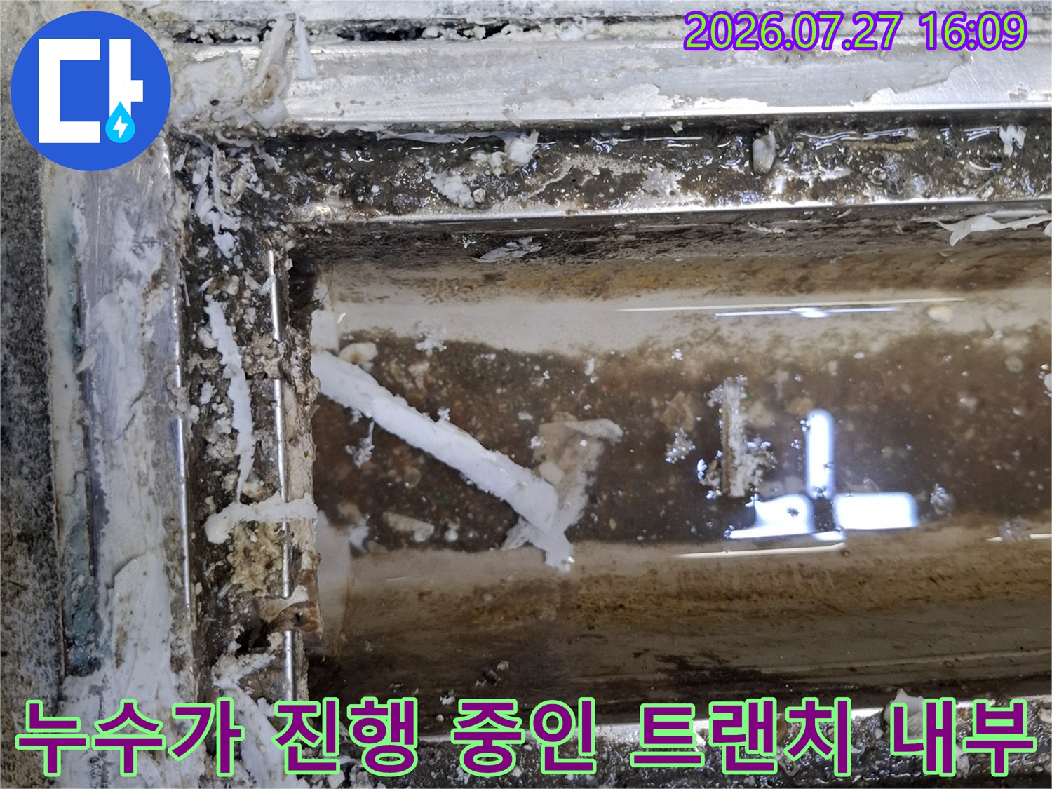 오염물이 섞인 물이 고여 있고 주변 시멘트 마감이 부식된 배수 트랜치-현장 사진