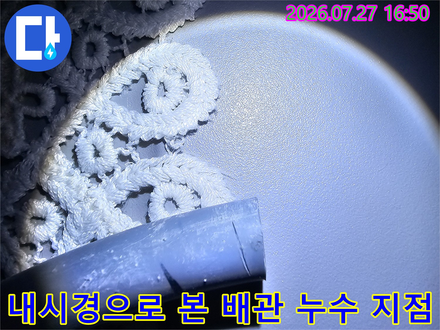 밝은 조명과 함께 촬영된 화장실 천장 내부의 파손 부위 배관 사진