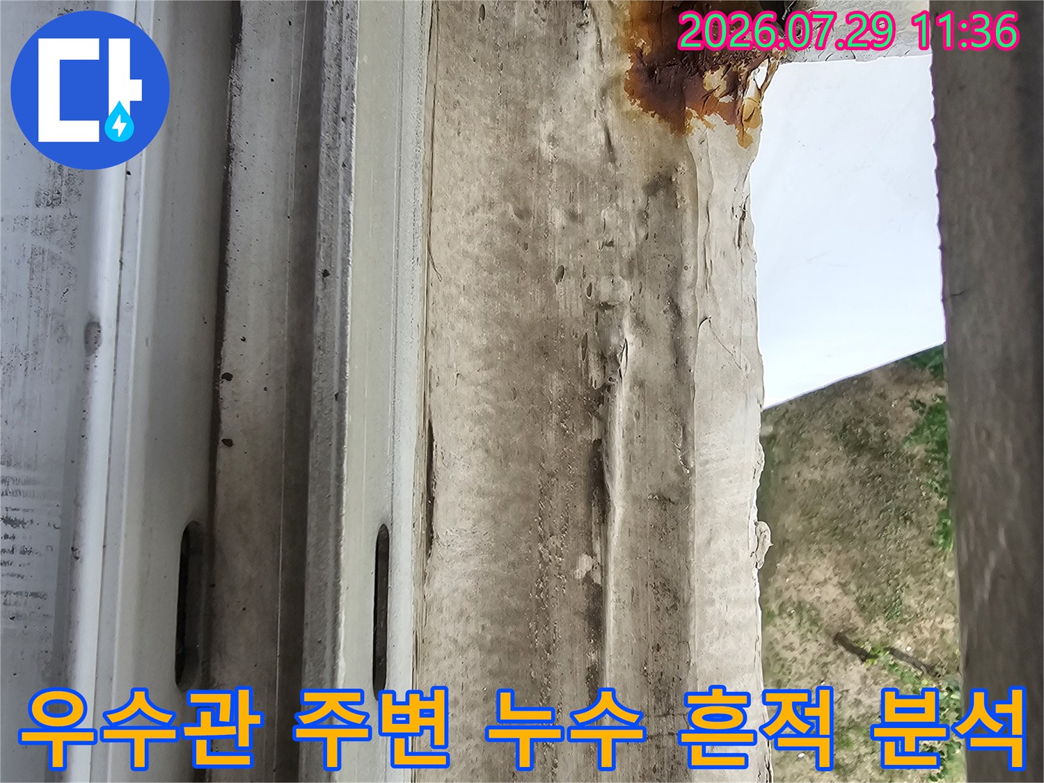 거친 질감의 마감재와 갈색 얼룩이 섞인 우수관 부위