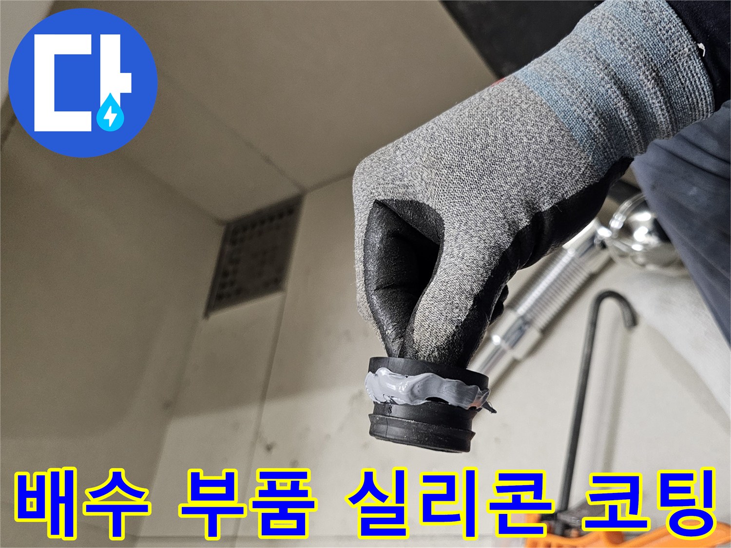 작업자가 장갑을 끼고 실리콘이 발린 배수 트랩을 들고 있음