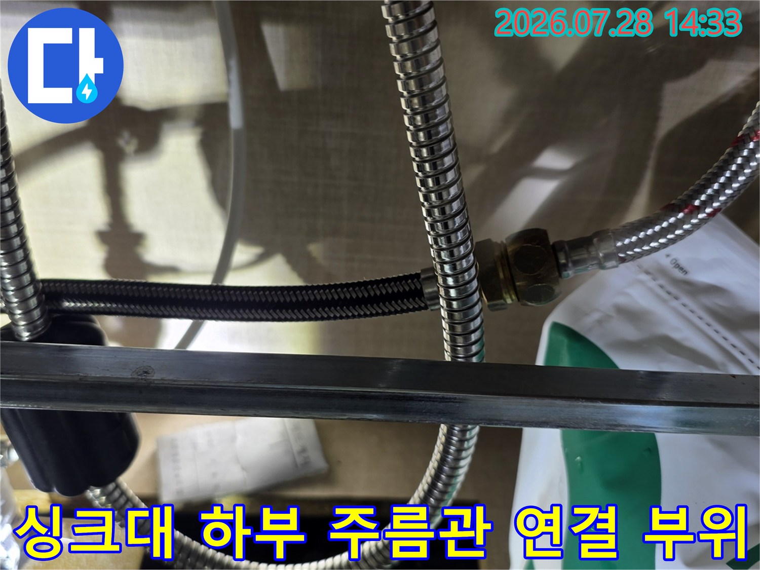 싱크대 아래쪽 스테인리스 주름관 배관과 연결 너트 부분이 보이는 모습