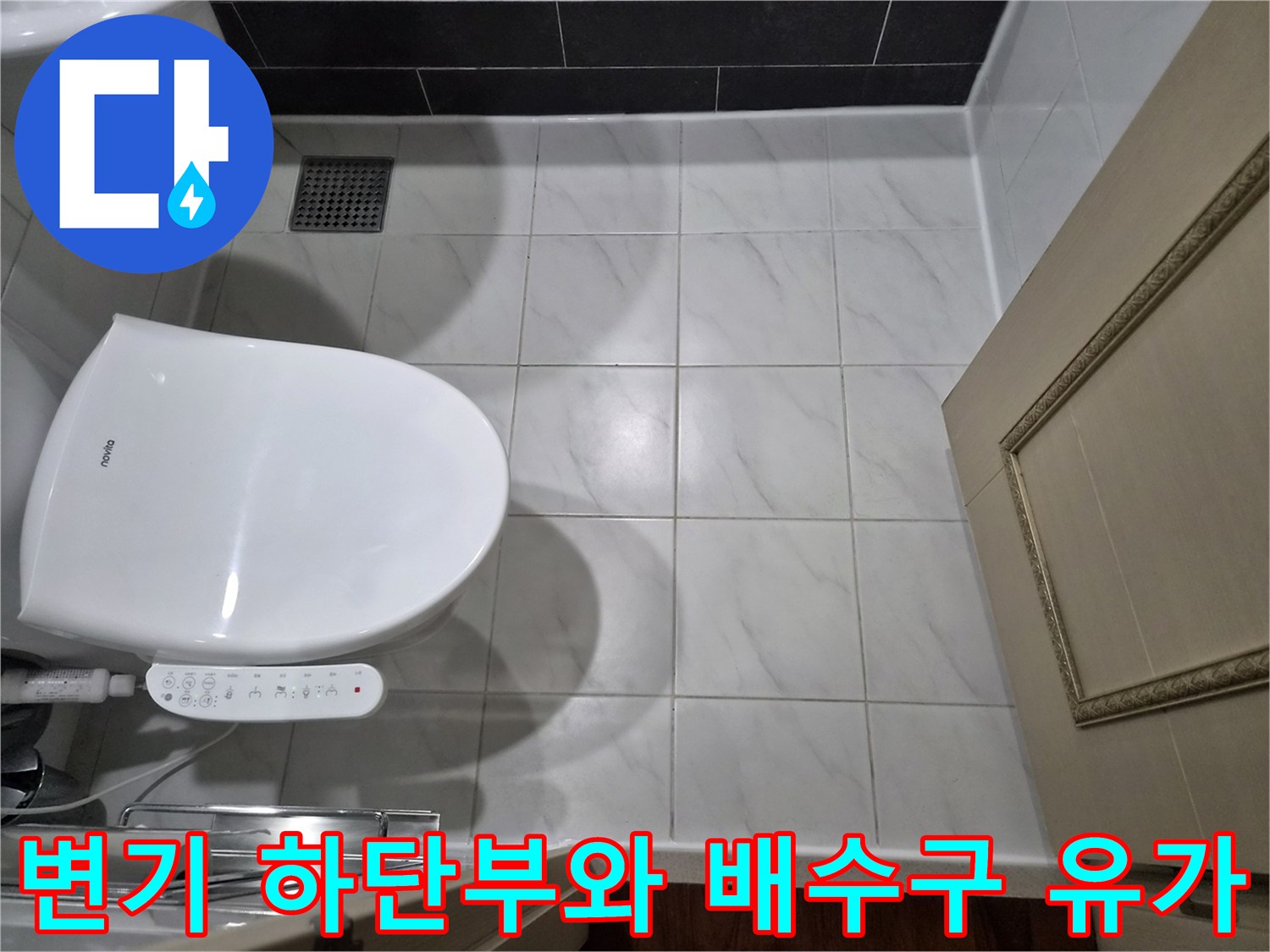 욕실 변기 주변의 타일 마감과 배수구 상태를 촬영한 이미지입니다.