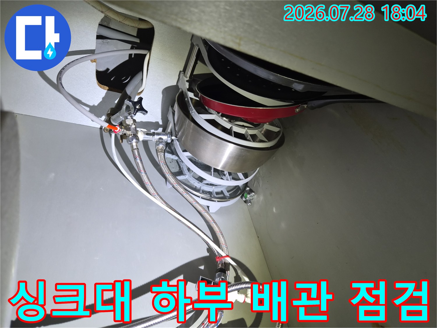 식기세척기와 연결된 여러 가닥의 급수 호스를 꼼꼼하게 살피는 장면입니다.