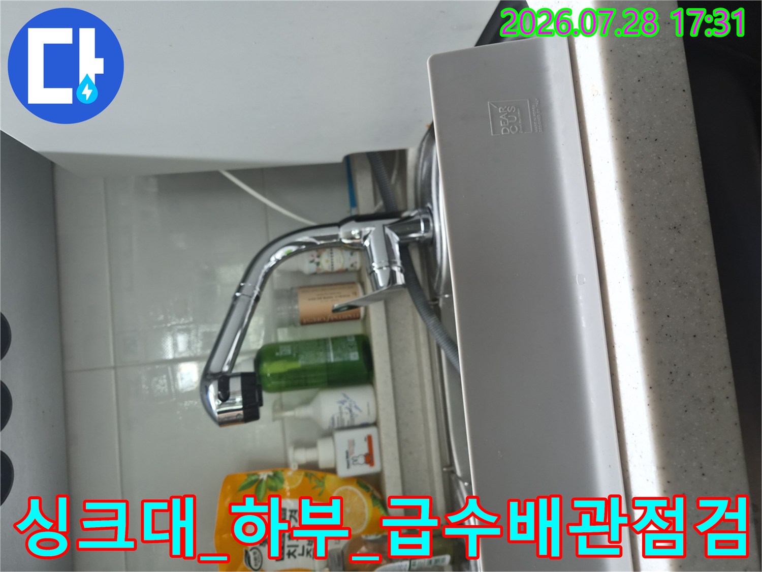 싱크대 하부 공간에서 식기세척기 연결 부품과 배관의 누수 여부를 꼼꼼히 확인하는 사진입니다.
