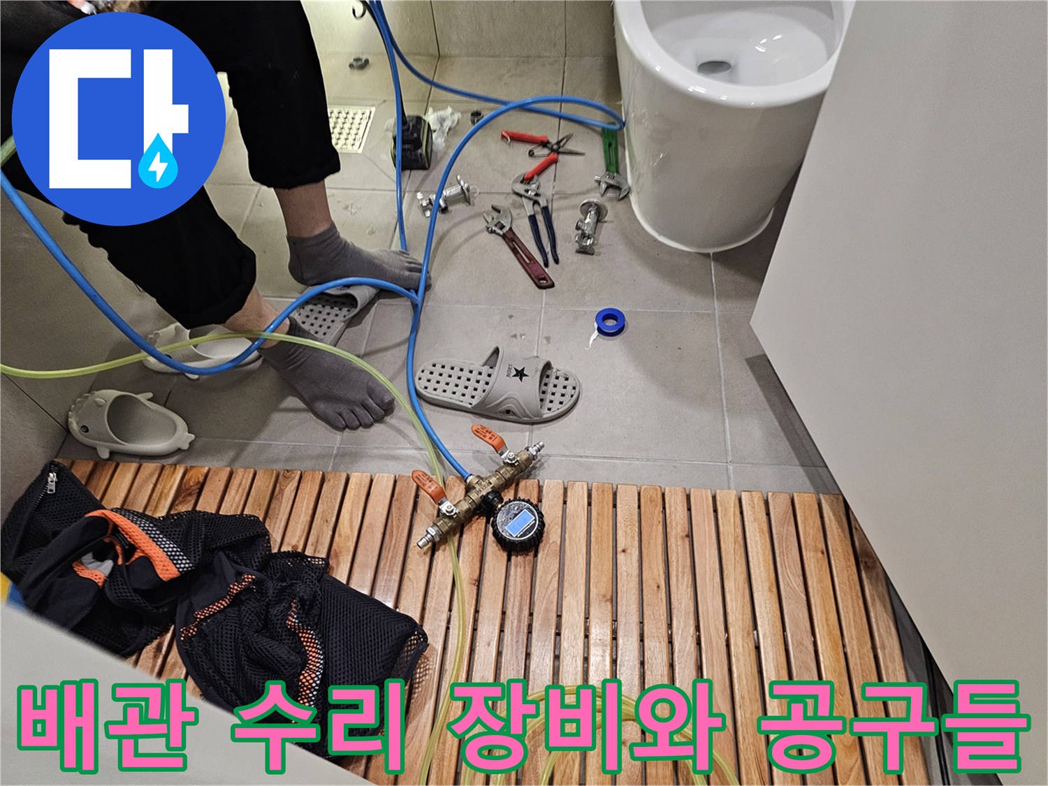 싱크대 아래 작업 공간에 놓인 렌치와 테프론 테이프 등 수리 자재